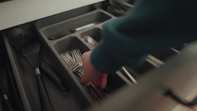Hand einer h&uuml;bschen Frau nimmt Gabel aus der Besteck Schublade zum Tisch decken.