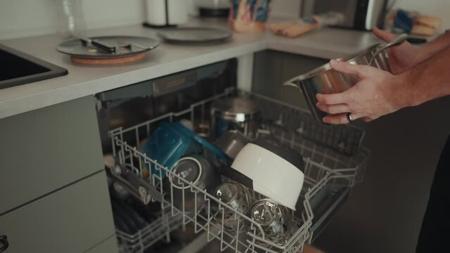 junger Mann r&auml;umt die Sp&uuml;lmaschine aus