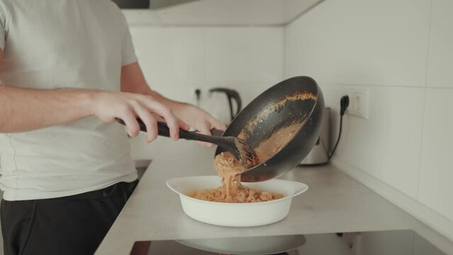 junger Mann beim zubereiten eines Nudel Auflaufes