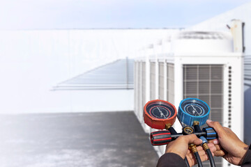 Air repair mechanic using measuring equipment for filling industrial factory air conditioners.	