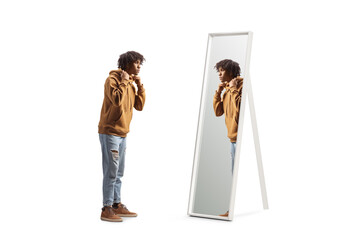 Full length profile shot of an african american young man standing in front of a mirror - obrazy, fototapety, plakaty