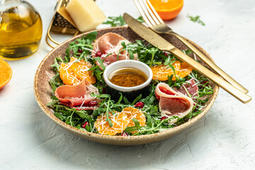 winter salad with arugula mandarins, prosciutto jamon and Parmesan cheese. place for text, top view