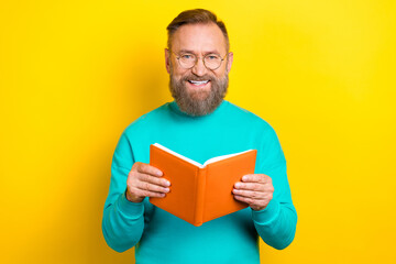 Photo portrait of nice retired man wear specs reading notebook busy drive dressed stylish cyan look isolated on yellow color background