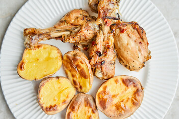 Chicken baked in pieces with potatoes and onion on a white dish. Home cooking. Healthy food, cooked without oil and salt.