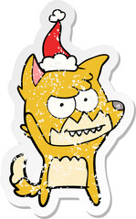 distressed sticker cartoon of a grinning fox wearing santa hat
