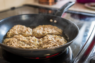 Frying crepe pancake pan with gratet potato on hot cooker hob