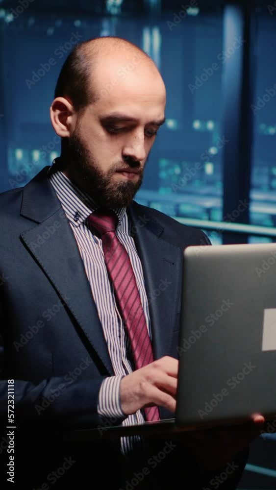 Poster vertical video: it manager technical support operator holding laptop in data center, working on comp
