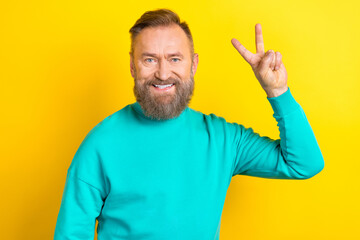 Photo of glad charismatic man wear comfort clothes demonstrate arm v-sign isolated on yellow color background