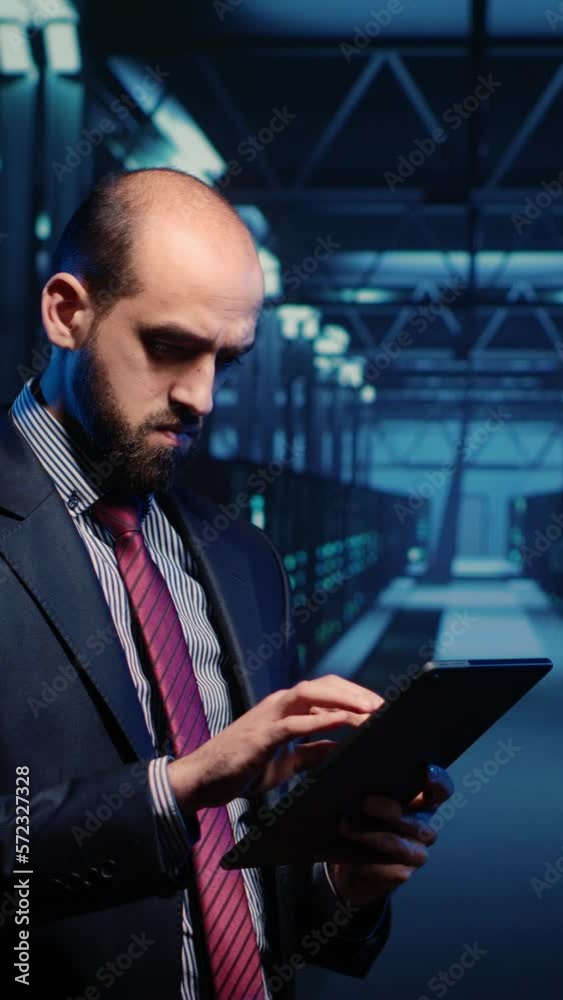 Poster vertical video: it engineer using tablet in high tech server room, planning networking computer syst