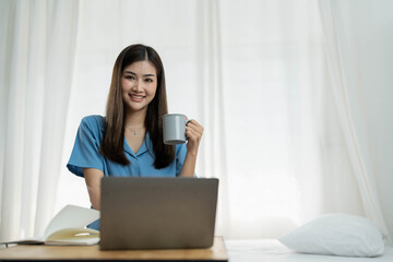 Fototapeta na wymiar Happy, Relaxing Young beautiful Asian female watching movie or series on notebook in emotional smile happily while laying on the bed in her bedroom. Day off, Chill out and leisure concept.