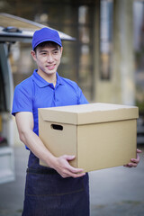 Deliver service. Man With Box in Car Outdoors Delivery Man in uniform holds parcel and phone car outdoors Delivery man taking parcels from The Delivery service.