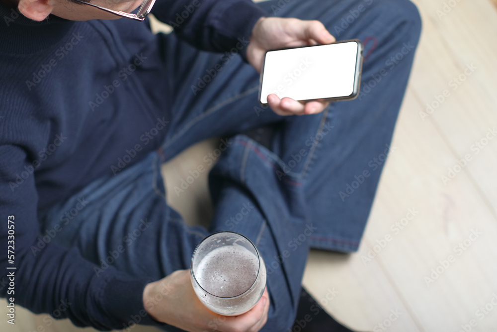 Wall mural a person holds a smartphone and a beer in his hands