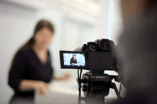 filming a video on professional camera or photoshoot of woman in black in White Hall back photographer blurred background advertising movie production life of ordinary people news incidents interview