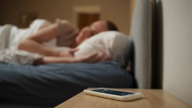 A woman wakes up from a phone call in bed and talks on the phone. 