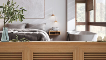 Wooden table top, cabinet, panel or shelf with shutters close up. Olive branch in vase and candles. Blurred background with japandi minimalist bedroom, interior design
