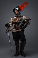 Portrait of medieval conquistador dressed in plate armour holding epee.