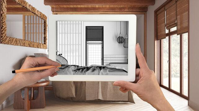 Hands holding and drawing on tablet showing wooden japandi bedroom details CAD sketch. Real finished interior in the background, architecture design presentation