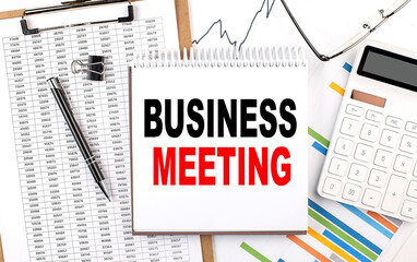 BUSINESS MEETING text on notebook with chart, calculator and pen