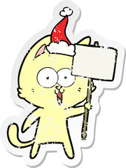 funny distressed sticker cartoon of a cat with sign wearing santa hat
