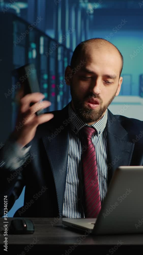 Poster vertical video: information security officer answering phone call in server room, using big data and