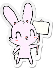 distressed sticker of a cute cartoon rabbit with sign