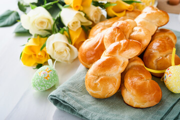 Fototapeta na wymiar Easter breakfast Holliday concept. Easter bunny buns rolls with cinnamon made from yeast dough with orange glaze, easter decorations, colored eggs on white spring background. Easter Holliday card.