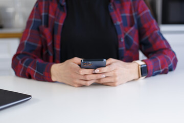 Young woman typing a message on smart phone. Unrecognizable female person using modern mobile phone for communication online