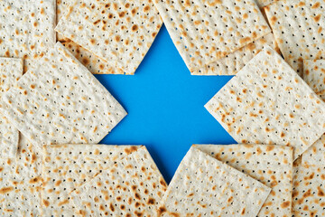 Passover celebration concept. Blue Star of David made from matzah, white and yellow roses, kippah...