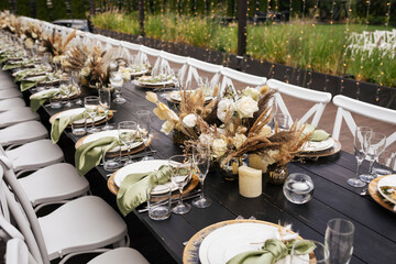 Wedding decorations. Served wedding table with golden plates, green napkins, decorative fresh and...