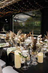 Wedding decorations.Close up of  decorative composition for wedding table with fresh and dried flowers, candles and and light bulbs. Celebration details, wedding outdoor
