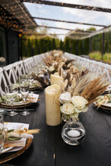 Wedding decorations.Close up of  decorative composition for wedding table with fresh and dried flowers, candles and and light bulbs. Celebration details, wedding outdoor
