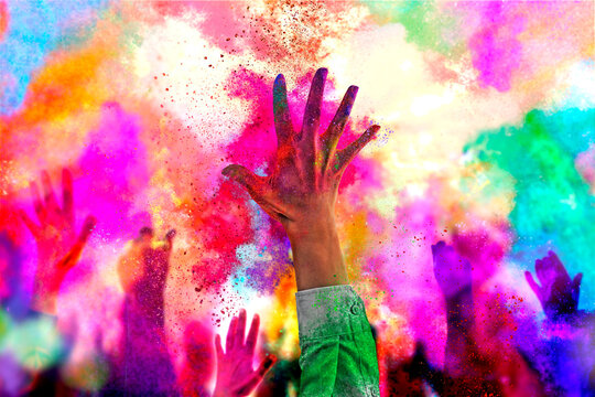 Holiday Holi concept.An explosion of multi-colored paint, bright vibrant pigments. Noisy dust and powder texture, flicker and shimmer noise. Background with hands for design