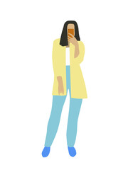 A girl standing with a smartphone. The brunette girl is wearing a yellow jacket and blue jeans.