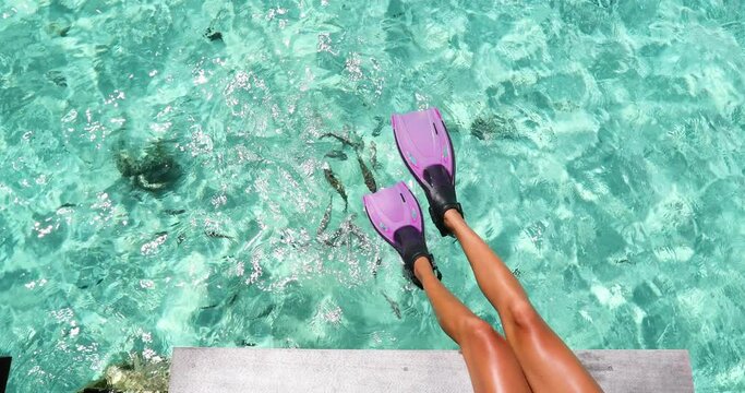 Travel vacation getaway concept. Woman wearing diving fins over sea. Girl enjoying beach vacation sitting by beach