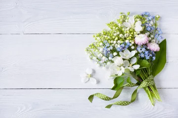 Fotobehang Bouquet of spring lilies of the valley, forget me not, flowers, daisies, apple blossoms and ribbon on white wooden background, copy space © tachinskamarina