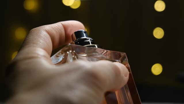 Man's hand sprays perfume from a bottle, close-up