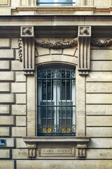 Paris ancient stone building facade with a French window, wrought iron grille and stucco fretwork