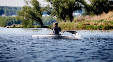 back athlete kayaker rowing in lake. kayak competition race