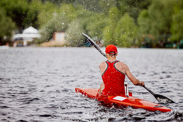 back athlete kayaker rowing kayaking competition. splashes and water drops