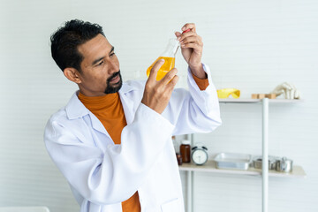 Male teacher in white lab coat using pipette bare hand carefully transfer chemical liquid in yellow...