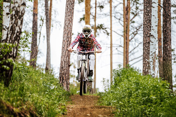 athlete mountain biker on forest trail in competition downhill