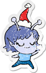 smiling alien girl distressed sticker cartoon of a wearing santa hat