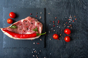 grilled beef steaks on stone background with copy space for your text concept. Raw piece of ribeye beef steak slate board wooden table hot pepper smile, spice, himalayan salt, tomato. Fresh barbecue.