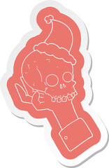 cartoon  sticker of a hand holding skull wearing santa hat