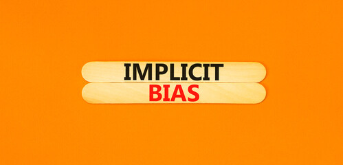 Implicit bias symbol. Concept words Implicit bias on wooden sticks. Beautiful orange table orange background. Business psychology implicit bias concept. Copy space.
