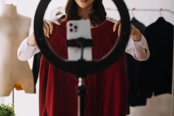 Beautiful lady blogger showing clothes in front of the camera to recording vlog video live streaming at her shop. Online Shopping Cart notion.