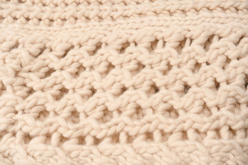 A fragment of beige knitted fabric, knitted from white sheep wool.