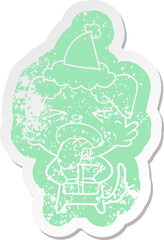 cartoon distressed sticker of a dog with christmas present wearing santa hat