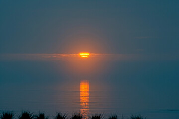 Sun in the Clouds over Water at Daybreak