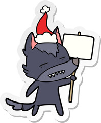 sticker cartoon of a wolf with sign post showing teeth wearing santa hat